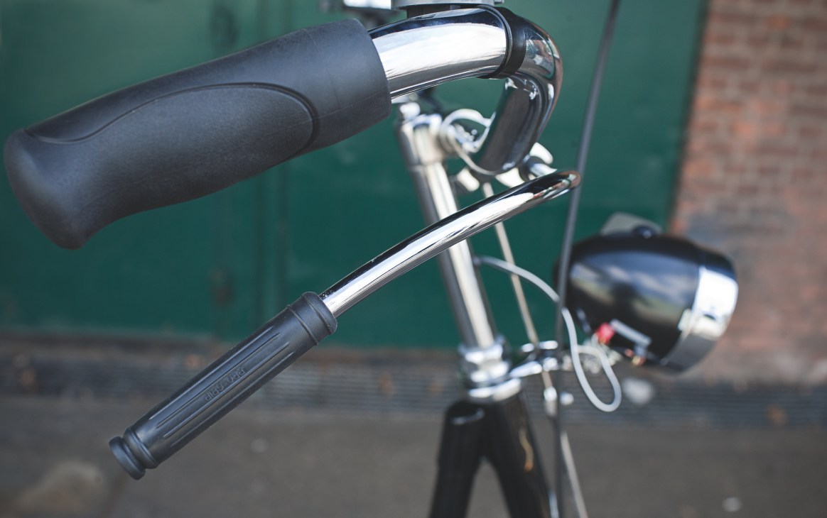Close-up of a Gazelle bicycle's handlebars and brake lever with black grips and chrome accents.