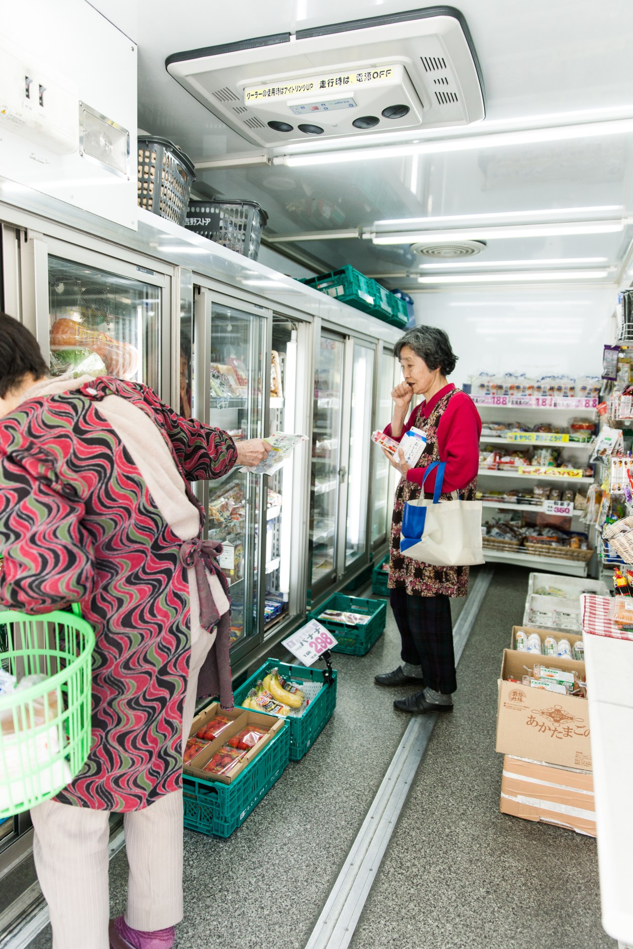 Customers shopping inside Yoshino Store's mobile grocery truck in Kawakami, Japan.