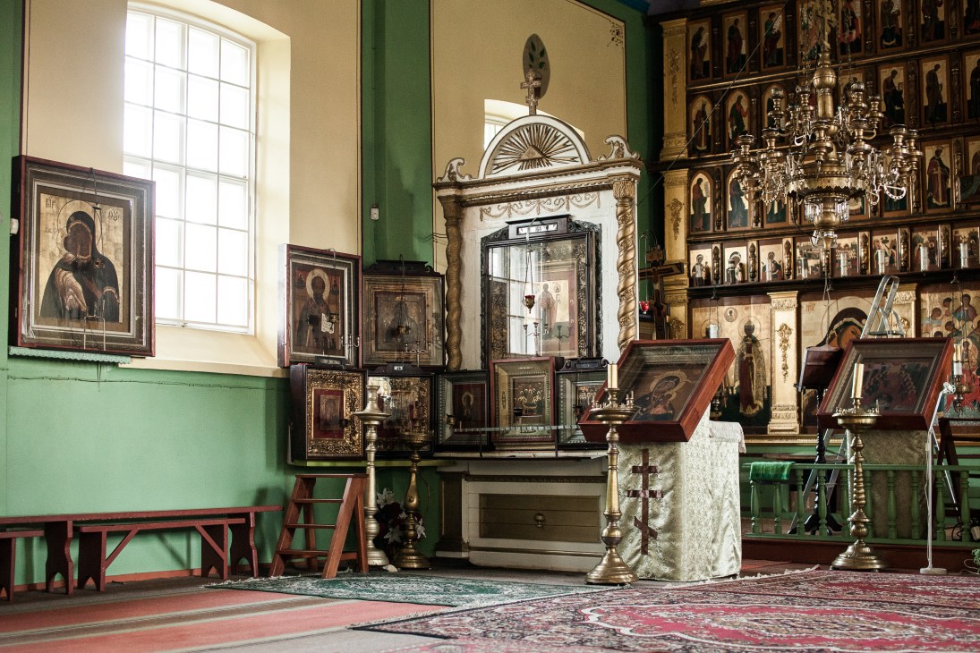 Interior of Old Believers church in Kolkja, Estonia, featuring ornate iconostasis with religious icons, candlesticks, and traditional Orthodox decorations.