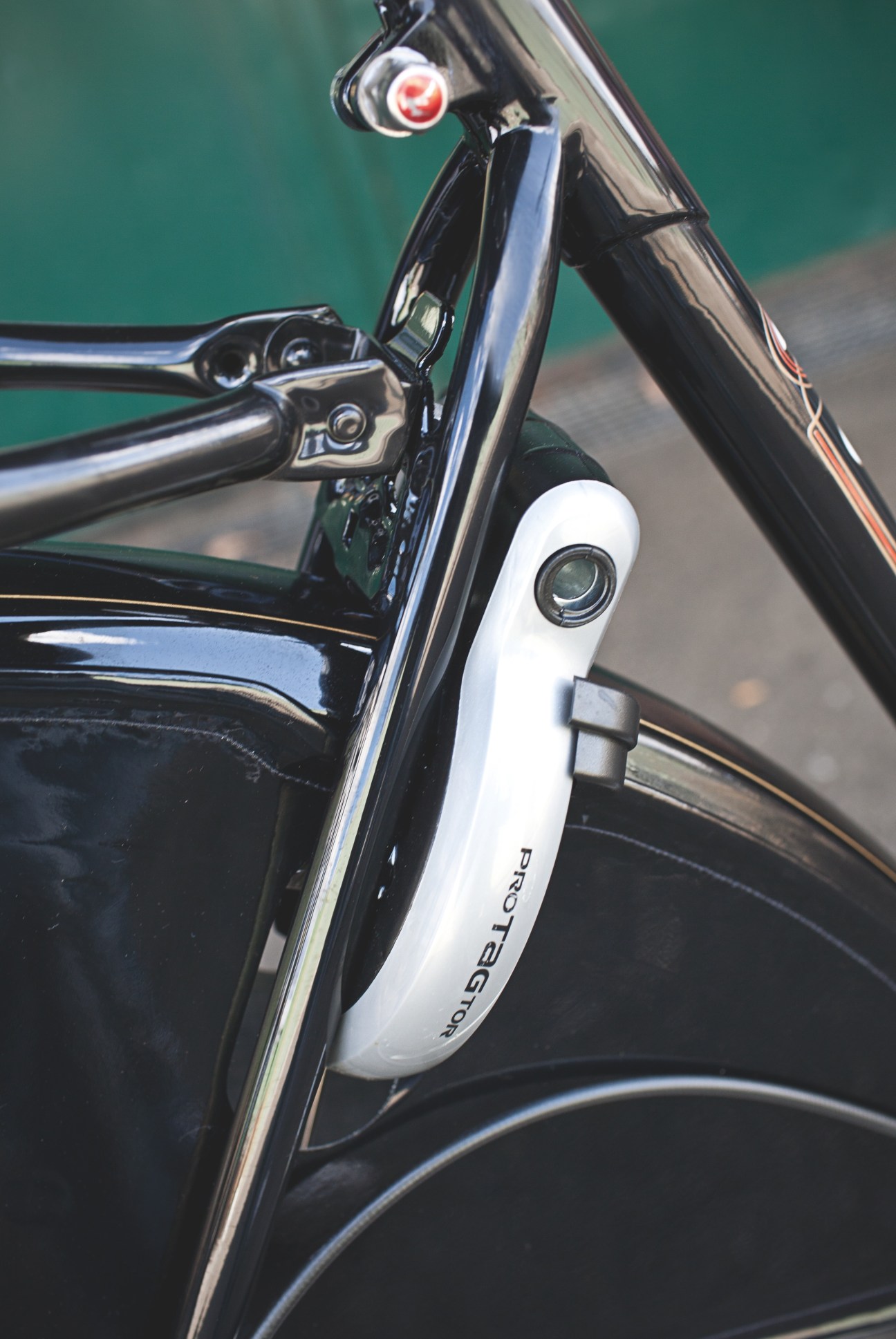 Close-up of a Gazelle bicycle's integrated lock and stand mechanism with white ProTagtor casing on black frame.