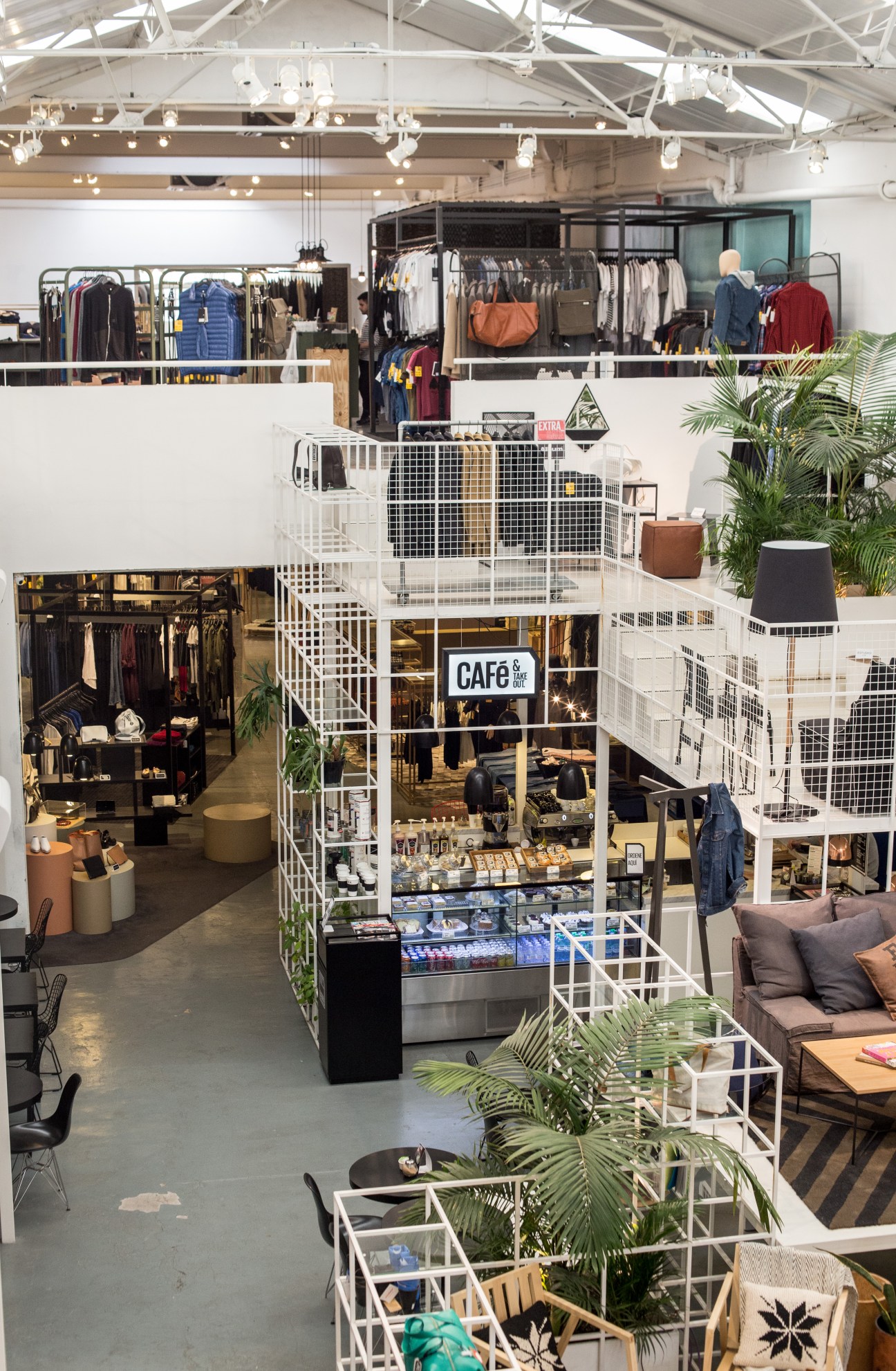 Interior view of Editor Market concept store showing multi-level white wire structure with clothing racks, café signage, and plant displays.