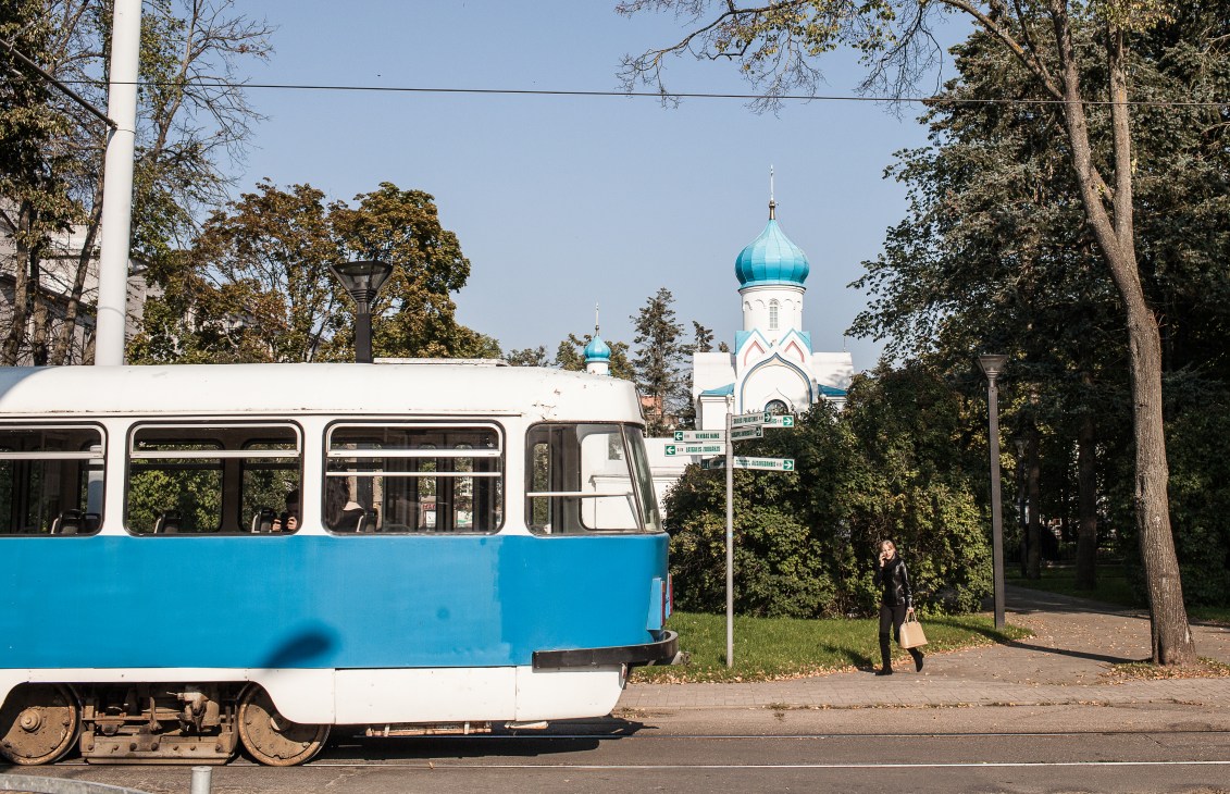 Blue and white Soviet-era tram on street with Orthodox church with turquoise domes in background, Daugavpils, Latvia