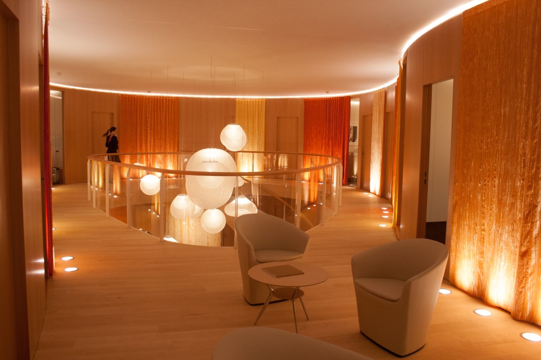 Interior of Hermès pavilion at Baselworld designed by Toyo Ito, featuring warm wood tones, curved lighting, and spherical display elements.
