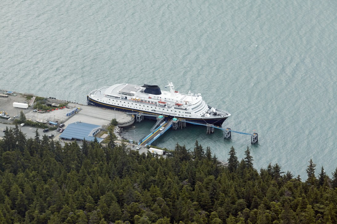 The M/V Columbia ferry docked at Haines terminal surrounded by coniferous forest and turquoise water.