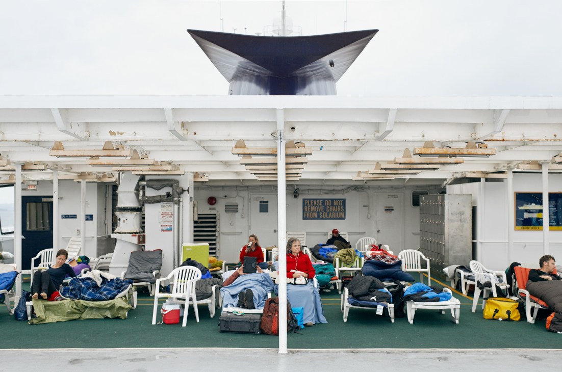 Passengers rest in sleeping bags and chairs on the solarium deck of the M/V Columbia ferry.