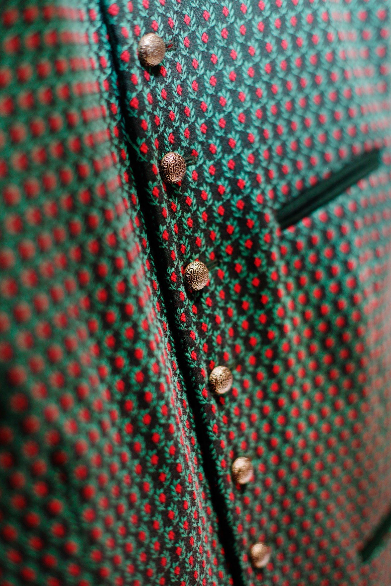 Close-up of a green and red patterned waistcoat with ornate brass buttons by Gottseidank.