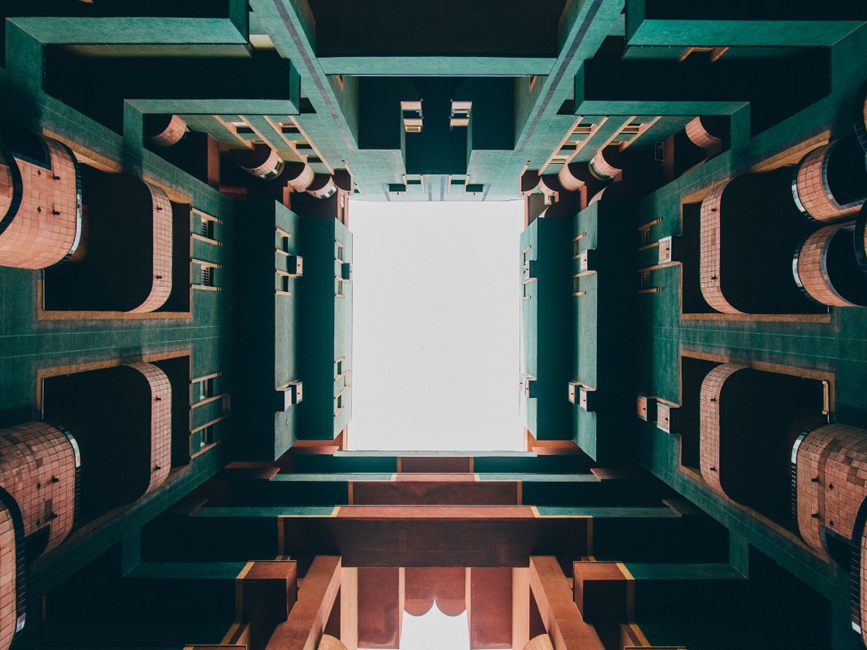 Overhead view of Walden 7's interior courtyard showing turquoise concrete walls, terracotta-coloured curved balconies, and sky opening above.