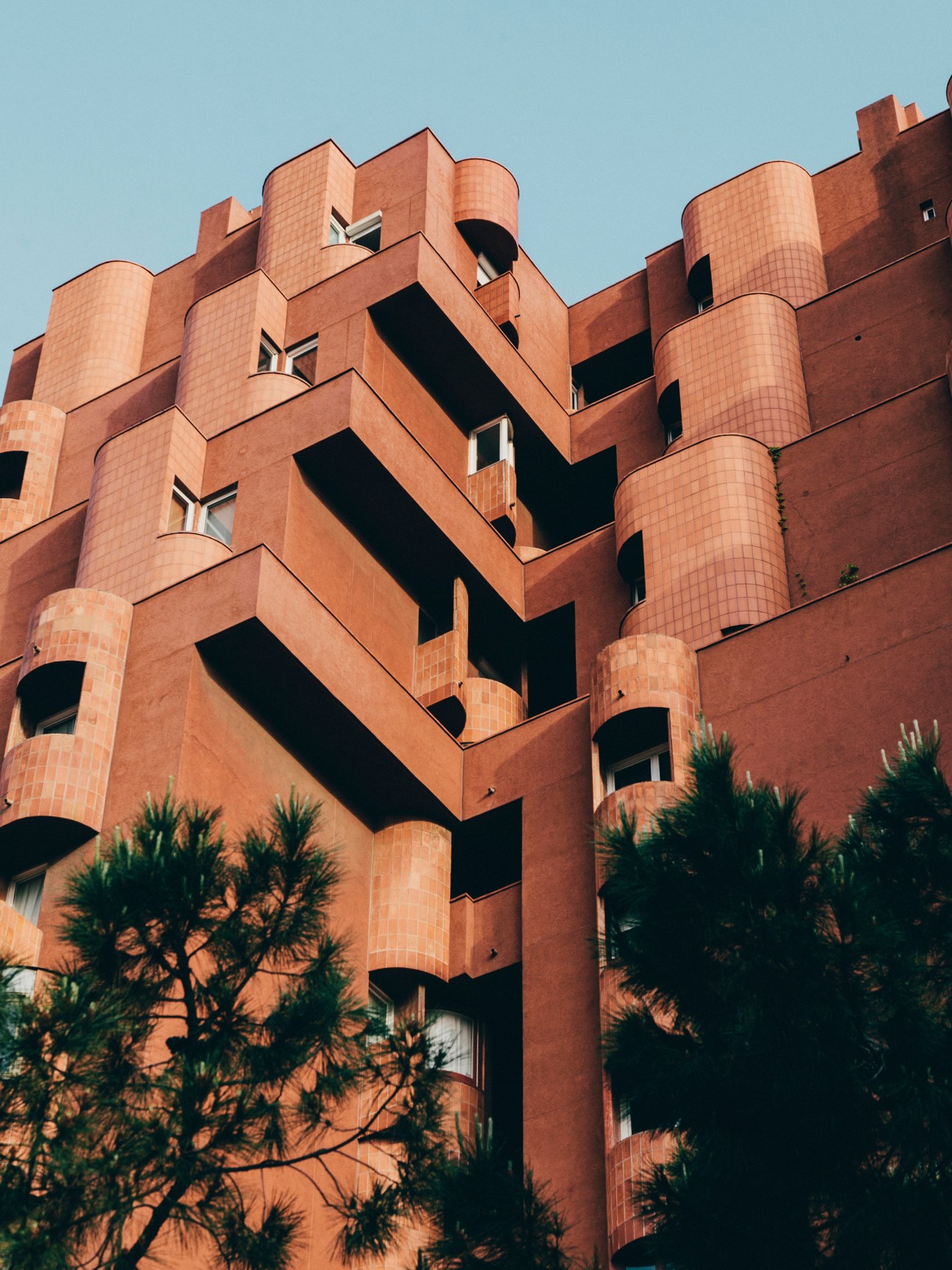 Terracotta-coloured facade of Walden 7 showing cubist design with cylindrical balconies and angular windows.