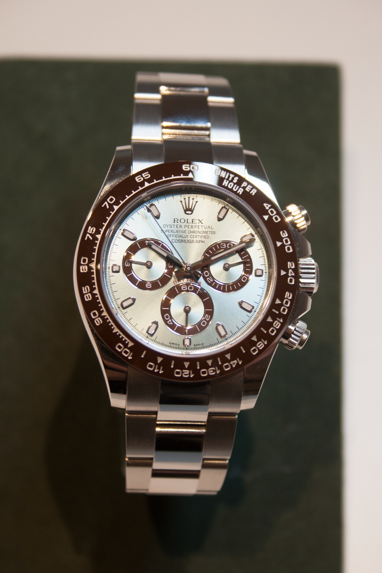 Rolex Oyster Cosmograph Daytona platinum chronograph watch with ice-blue dial and chestnut brown bezel on green background.