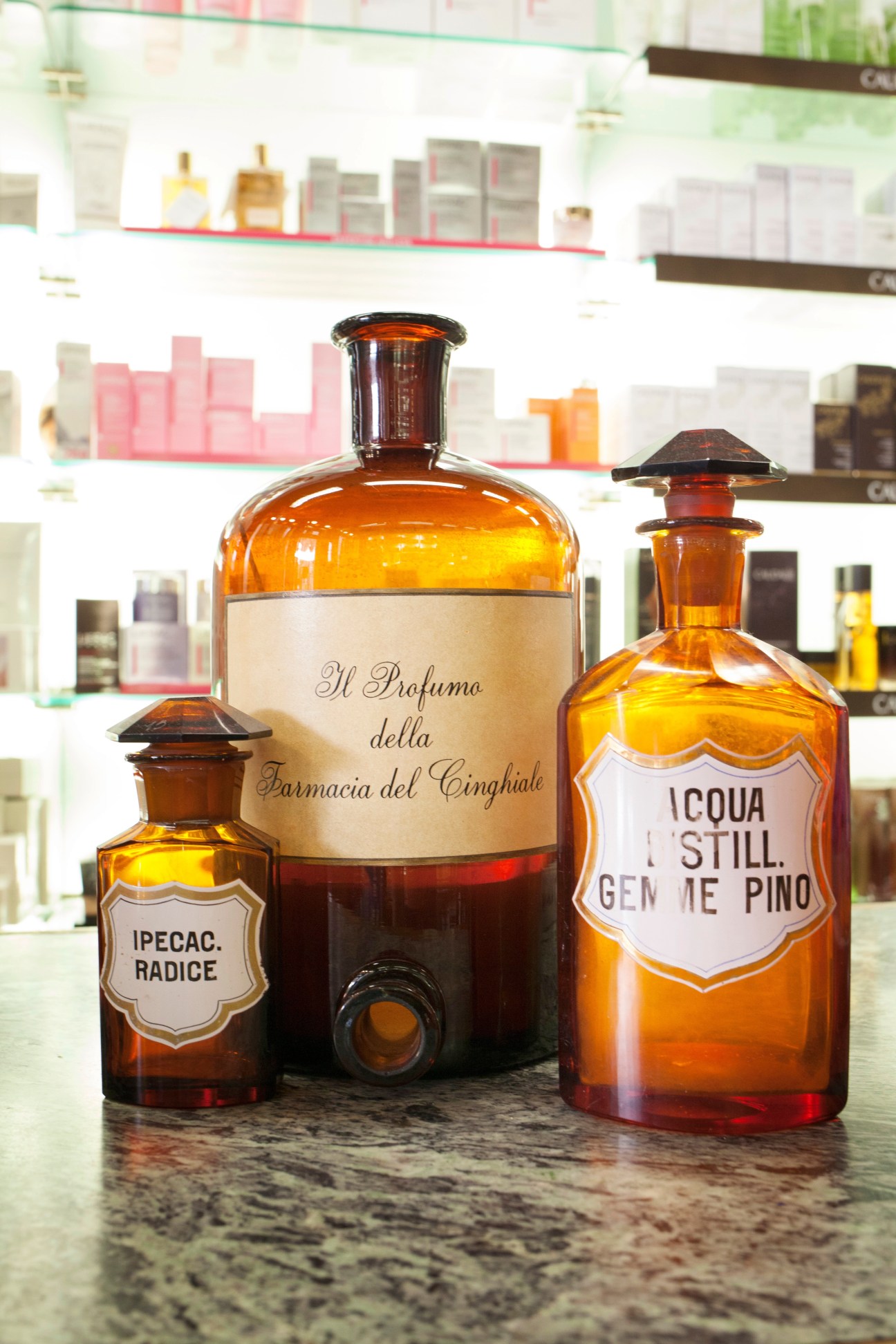 Three amber glass bottles of perfume and natural products displayed at Farmacia del Cinghiale in Florence.