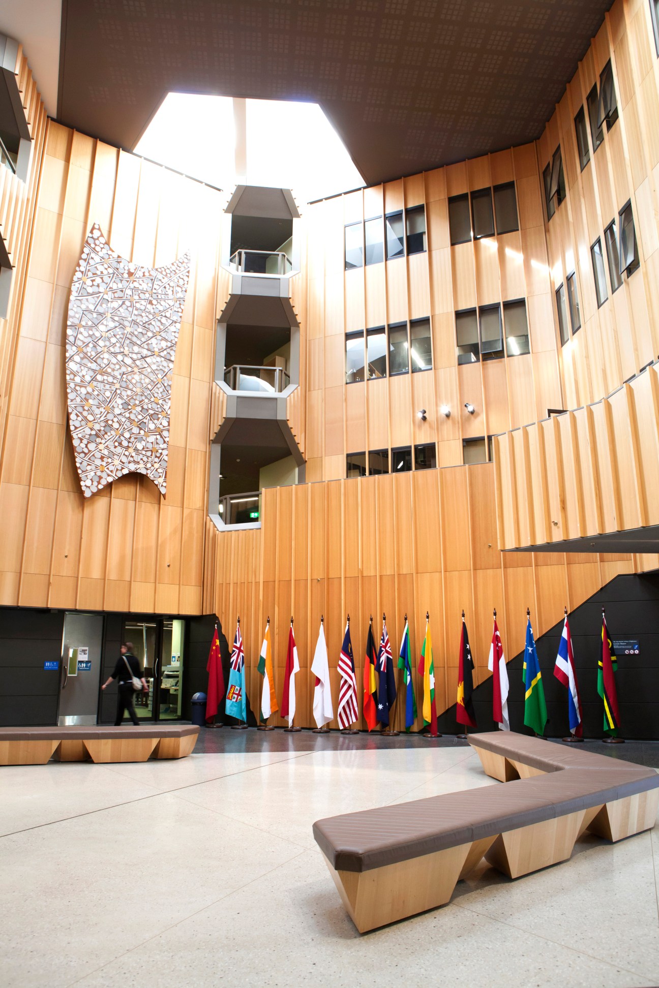 Interior courtyard of the Hedley Bull Building with wood paneling, skylight, international flags, and central atrium design.