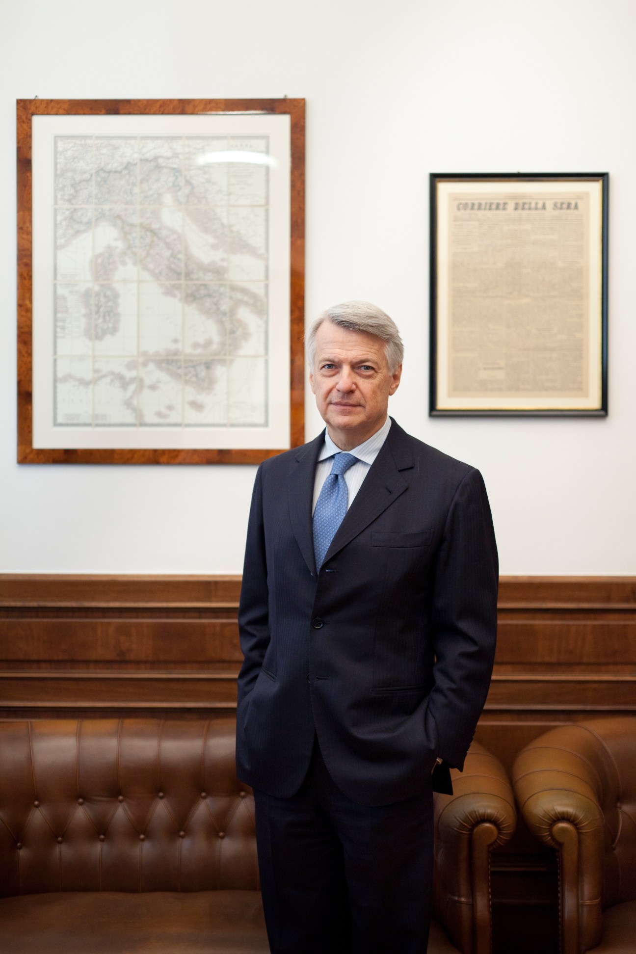 Ferruccio de Bortoli, editor in chief of Corriere della Sera, stands in his office wearing a navy suit and blue tie.