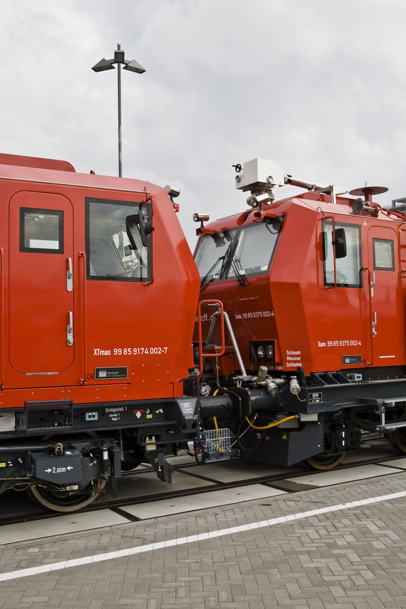 Red fire-brigade train cars with equipment mounted on roof, commissioned by Swiss SBB railway.
