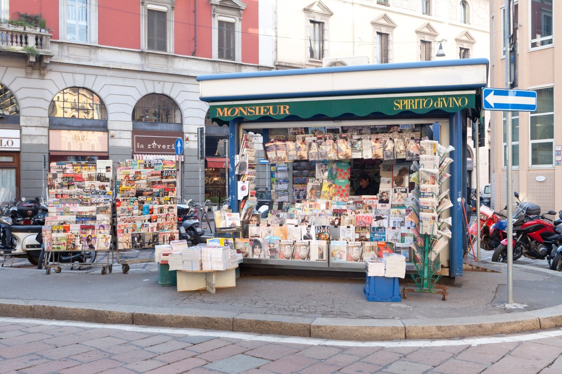 Edicola Prestinari newsstand in Milan displaying magazines and newspapers on its blue storefront.