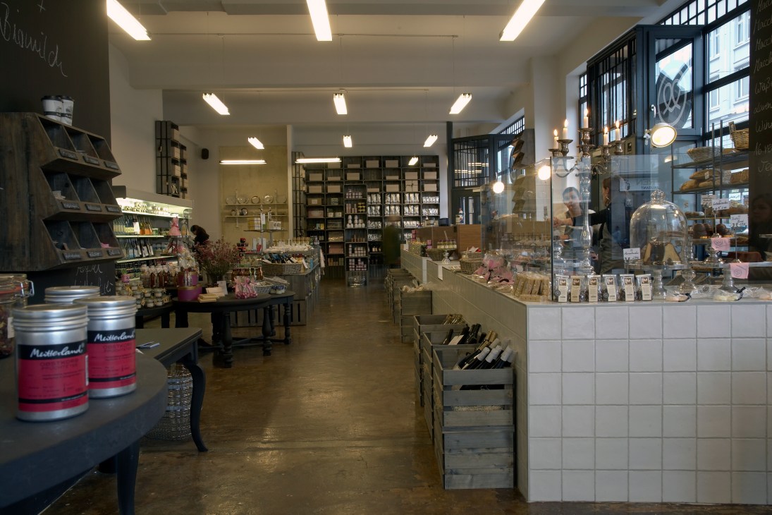 Interior of Mutterland deli in Hamburg showing shelving, display cases, and products with German kitsch decor elements.