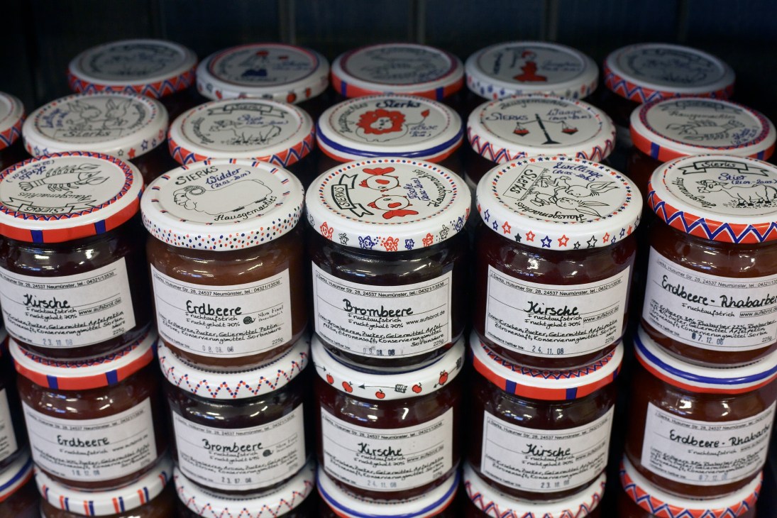 Jars of Freche Früchtchen homemade marmalade with hand-drawn labels and decorative fabric-covered lids.