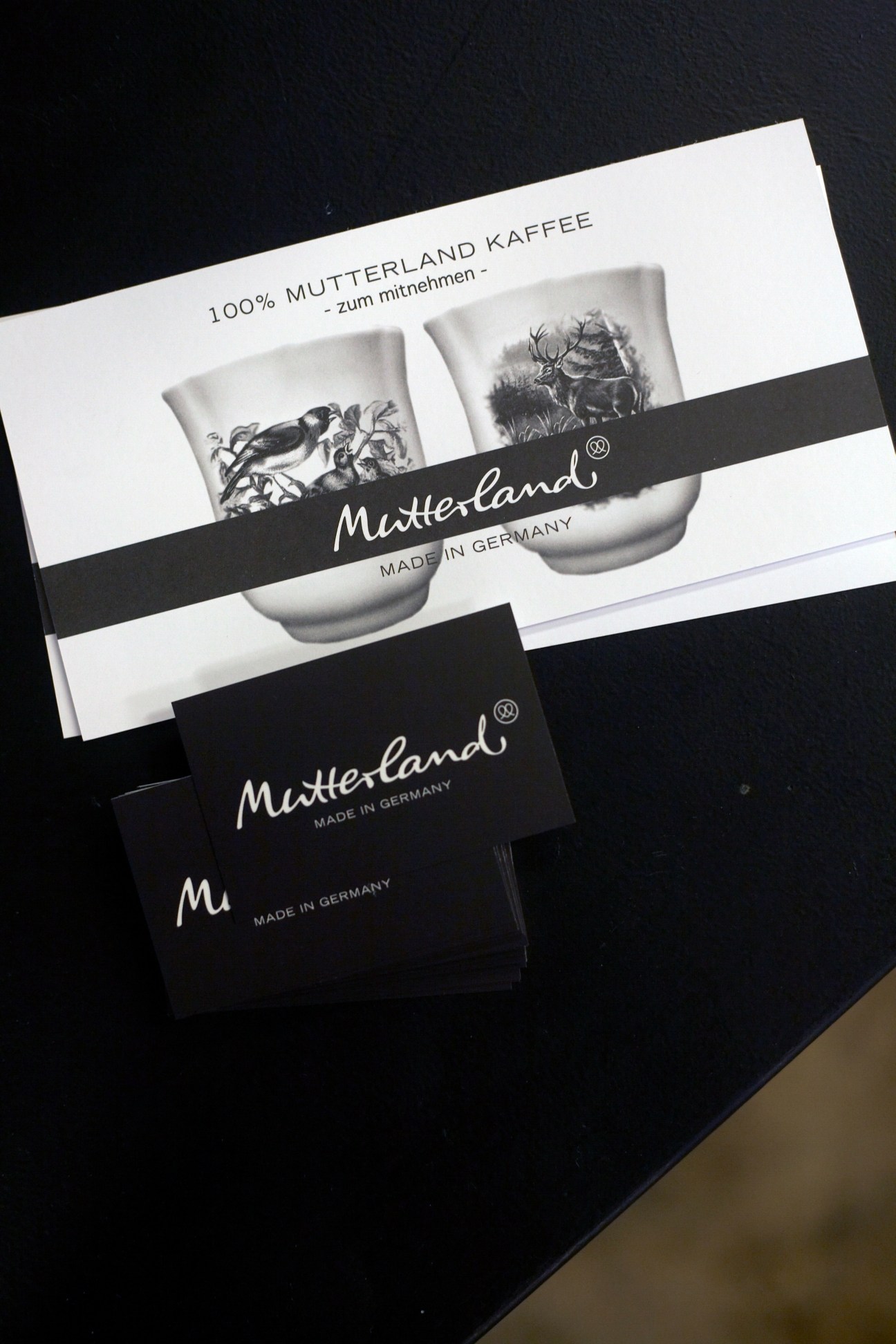 Mutterland coffee packaging with black and white branding and animal illustrations on dark background.
