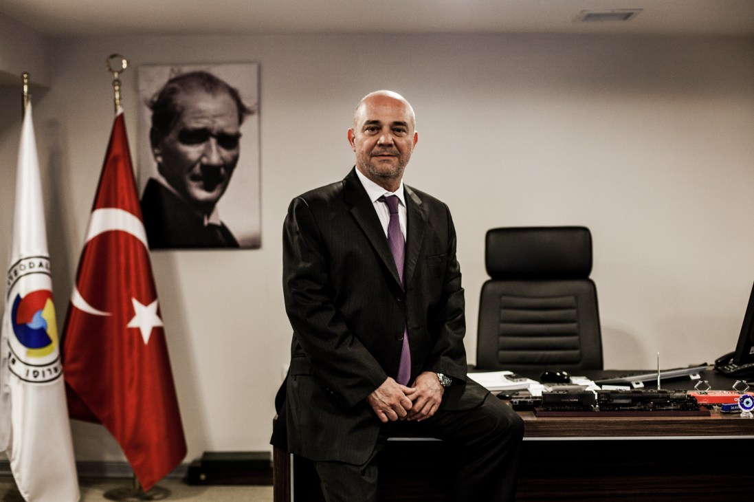 Huseyin Isteermis, general manager of BALO, sits at his desk in the company's Izmir headquarters with a Turkish flag and portrait behind him.