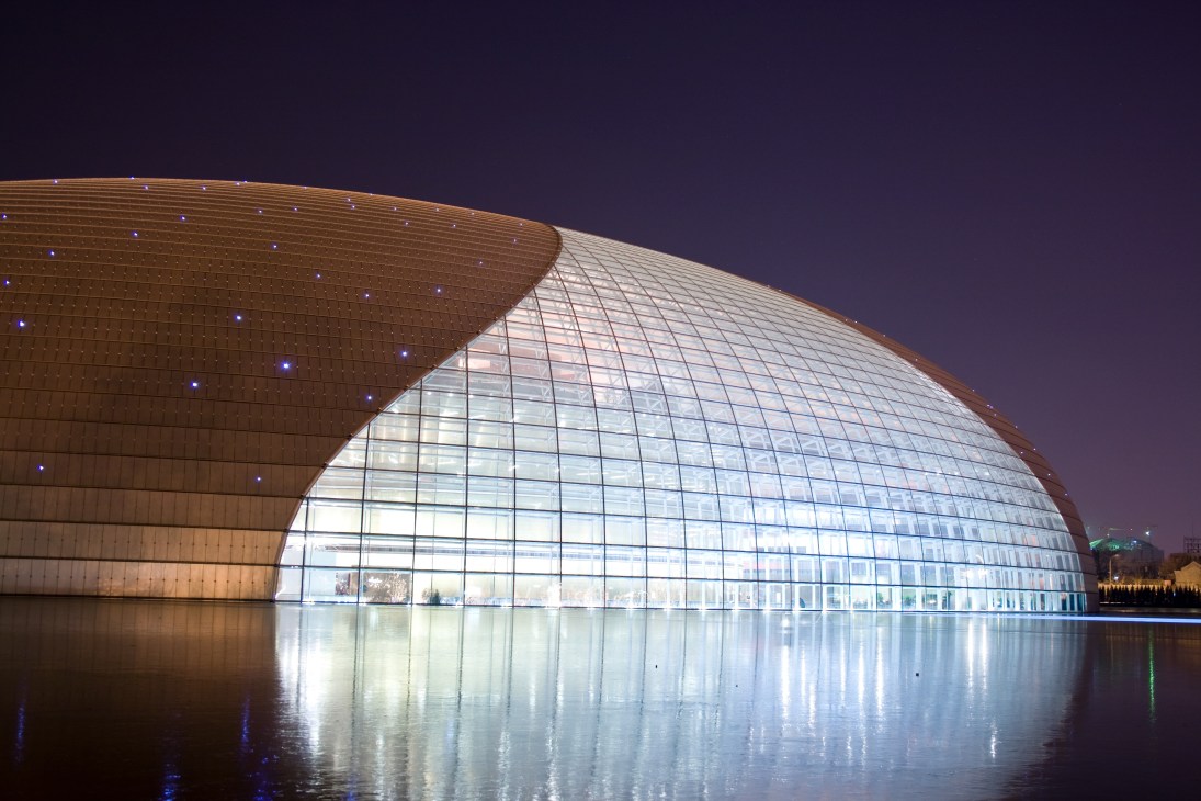 Illuminated National Centre for the Performing Arts at night with reflection in water, designed by Paul Andreu.