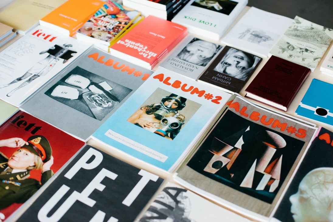 Collection of art books and publications displayed on a table, including colorful volumes with orange and blue covers.