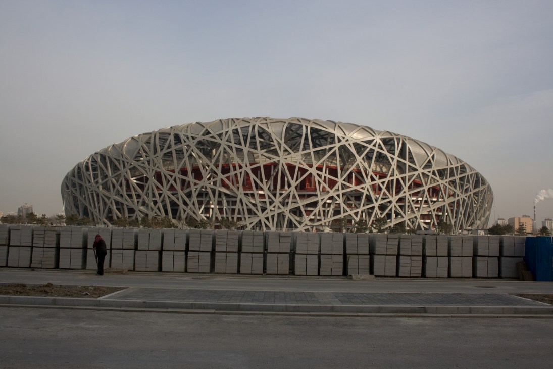 Herzog & de Meuron's National Stadium, known as the Bird's Nest, with interwoven steel framework and red interior visible through the latticed structure.