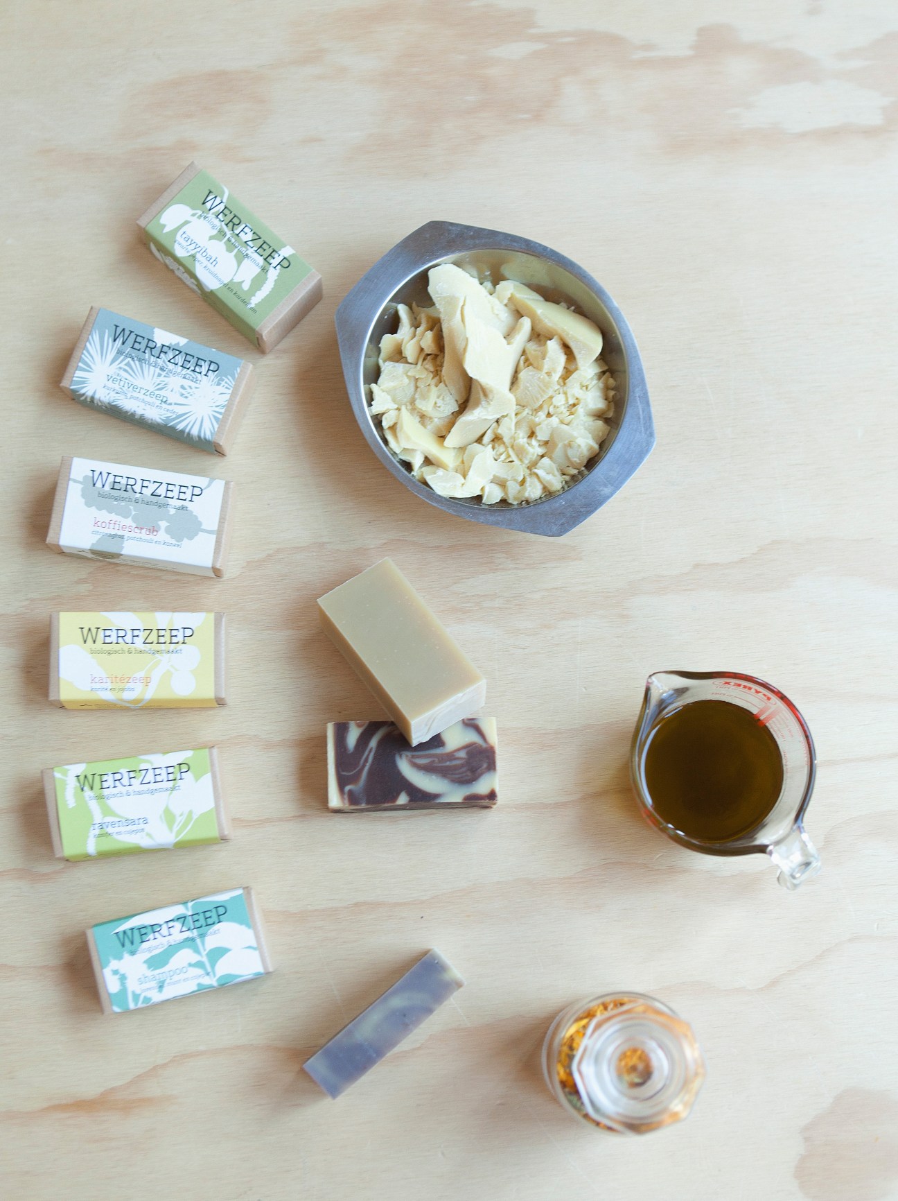 Werfzeep organic soap products displayed on a wooden surface with ingredients and oils.