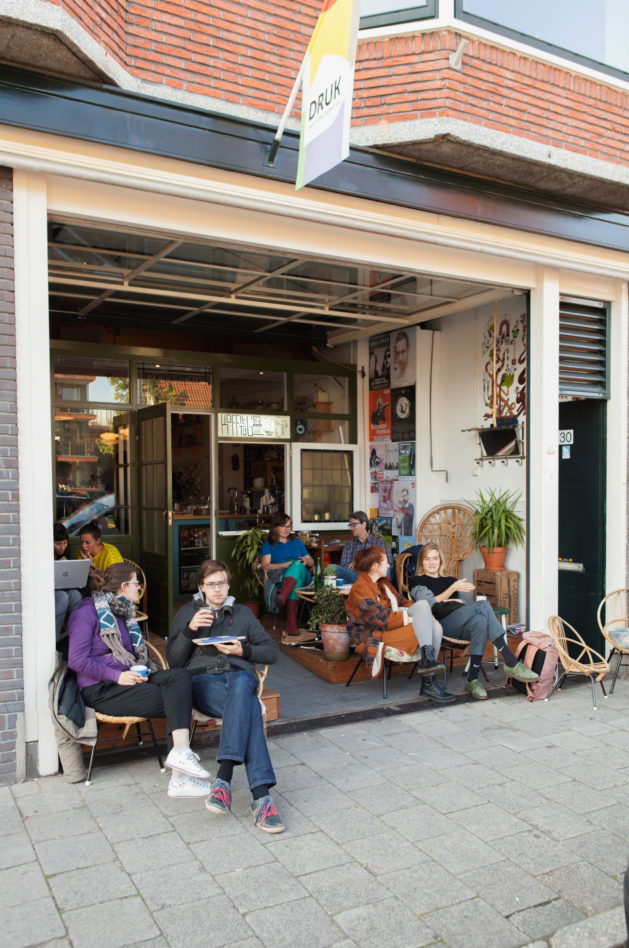 People seated outside Druk shared workspace enjoying beverages at Koffie Leute Brauhaus café.