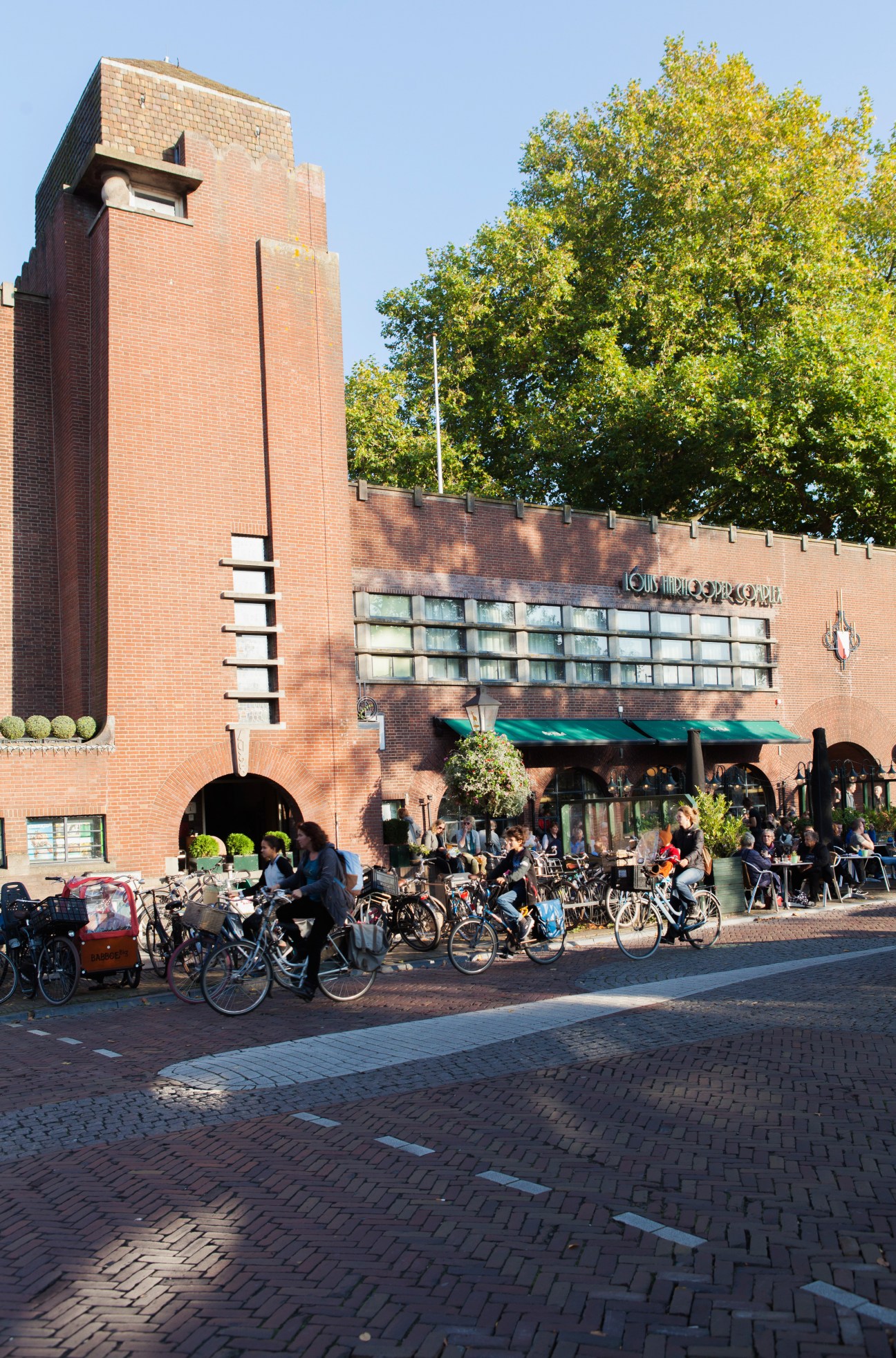 Louis Hartlooper Complex, a brick cultural centre in Utrecht with outdoor seating and cyclists in front.