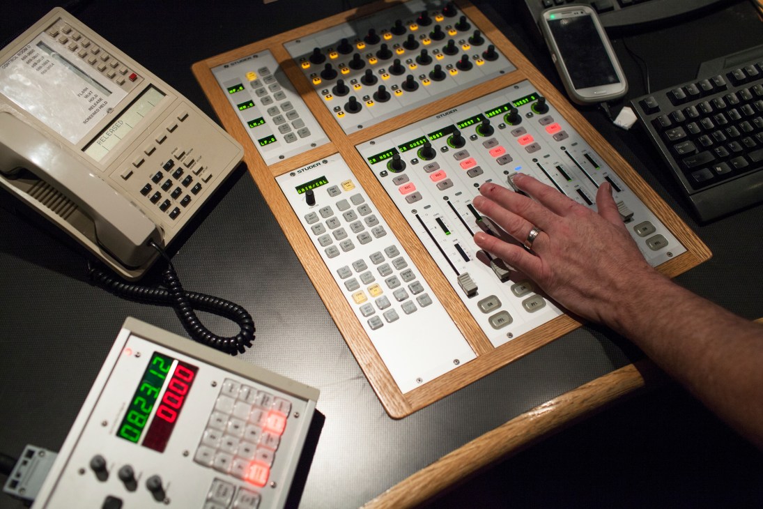 Hand operating radio control room equipment with buttons, dials and illuminated controls