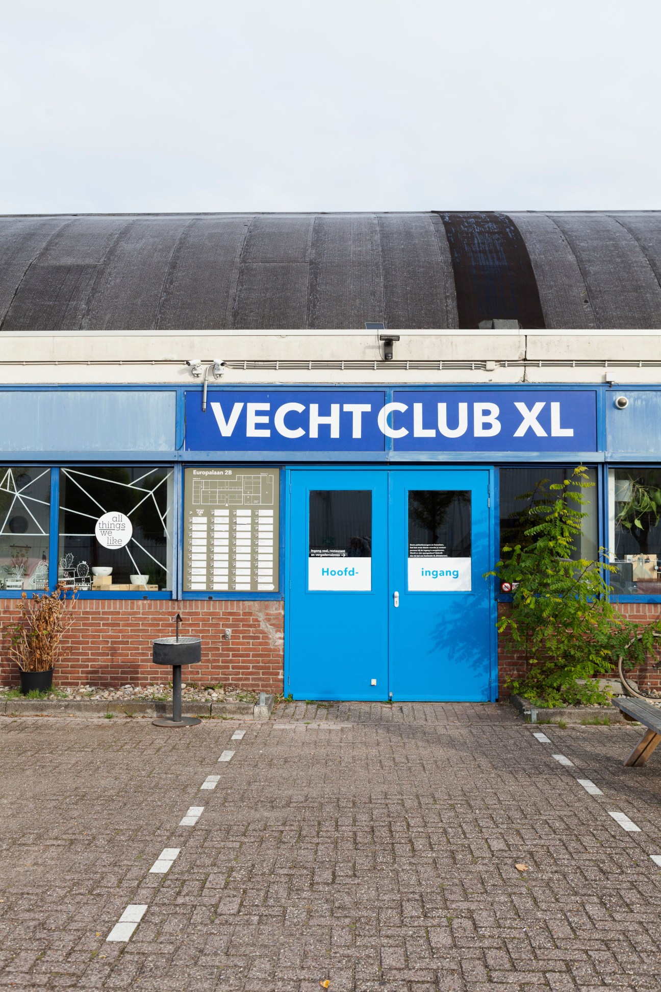 Exterior of Vechtclub XL creative workspace with blue entrance doors and industrial curved roof.