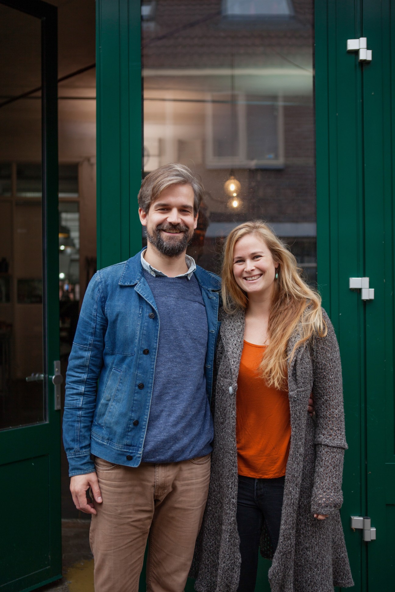 Laurens van der Wee and Evelien van Zonneveld, owners of Werfzeep organic soap brand, standing in front of a green storefront.