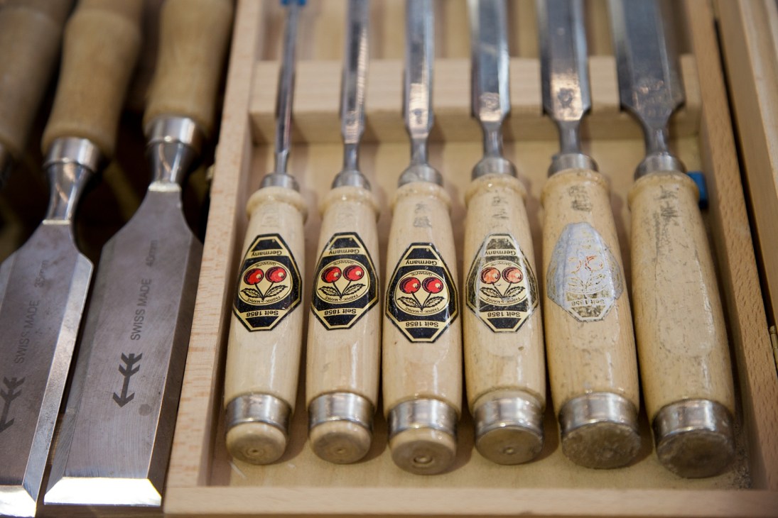 Row of carpenter's chisels with wooden handles and metal ferrules, some showing vintage maker's marks.