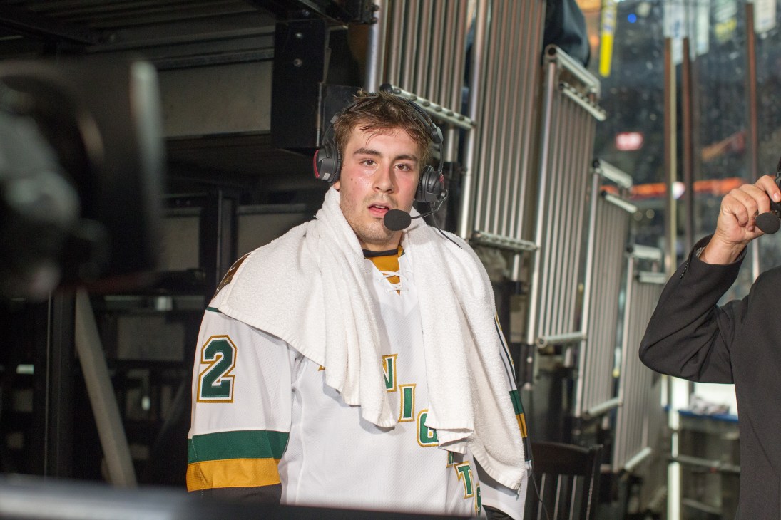 Evan Bouchard drying off with a towel during a post-match interview wearing a white hockey jersey