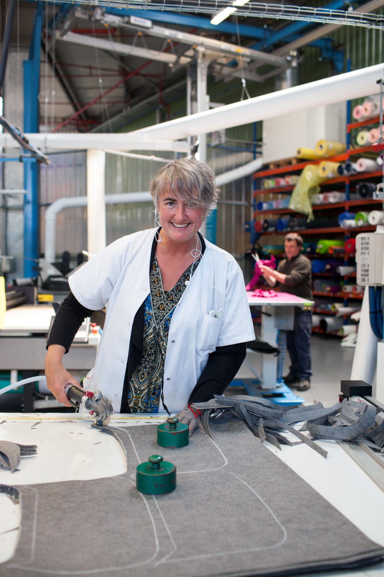 Woman using a power tool at a workstation in an industrial factory setting.