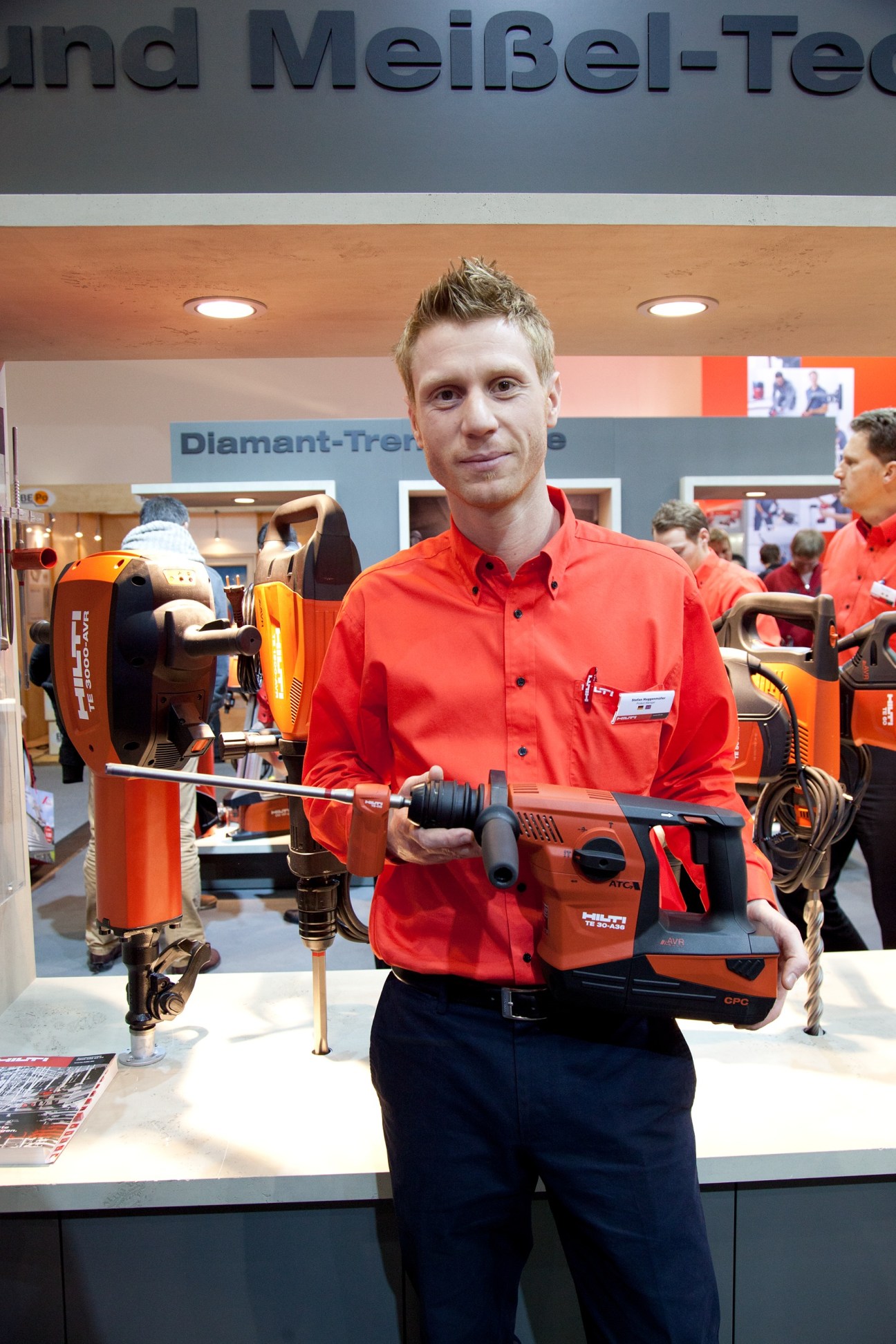 Hilti staff member demonstrating a cordless hammer drill at the BAU trade fair booth.
