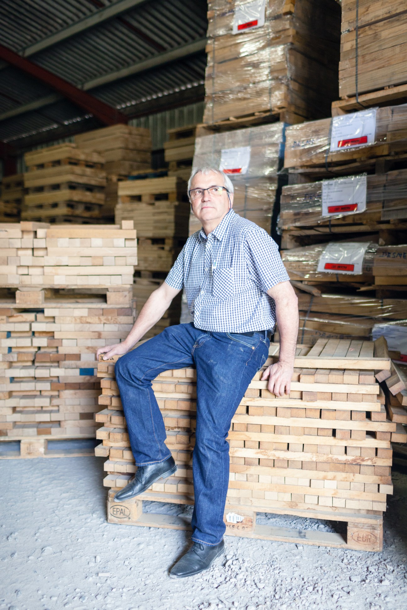 Alki CEO Peio Uhalde sits on stacked wooden pallets in a factory warehouse.
