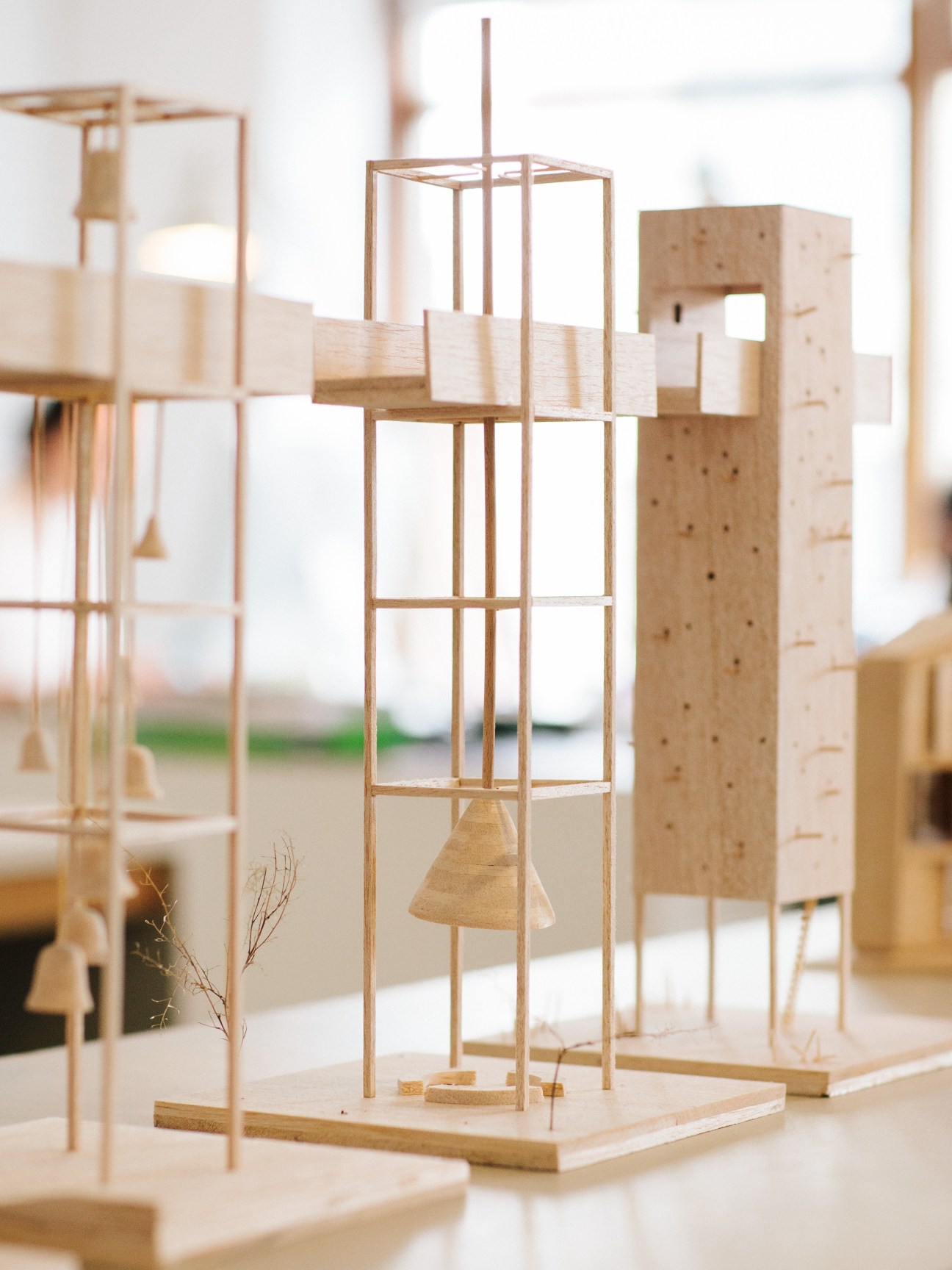 Wooden architectural model of a bell tower with vertical frame and hanging bell details.