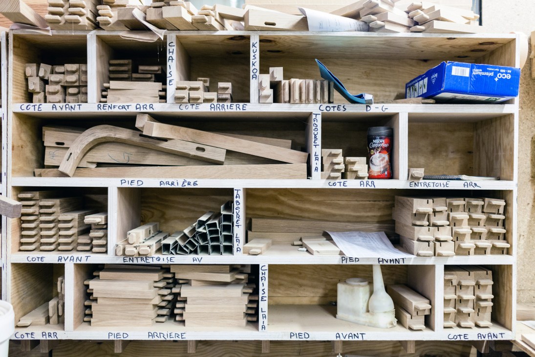 Wooden shelving unit filled with organized furniture parts and components labeled in French.