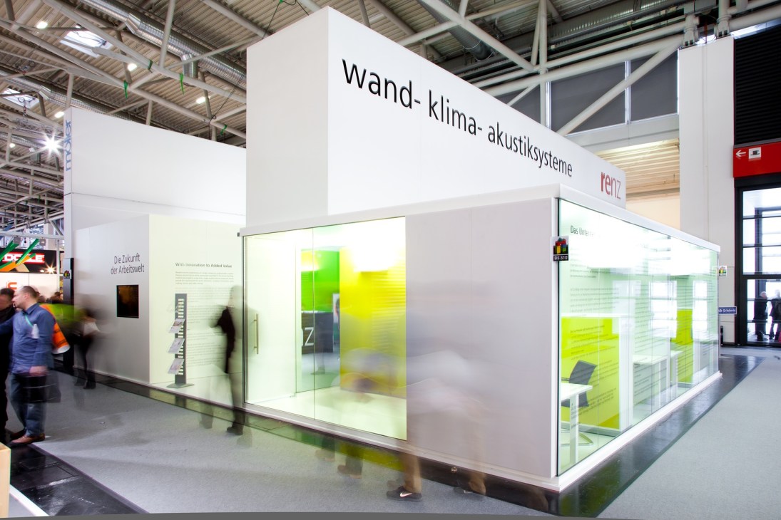 Exhibition booth with white walls and green interior display at BAU construction fair.