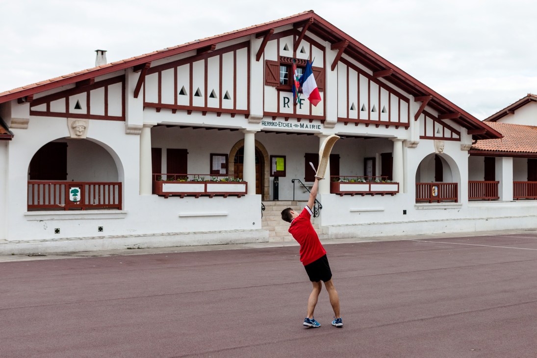 A player throws a pelota ball against a traditional Basque half-timbered building in Guethary during a game of Jai Alai.