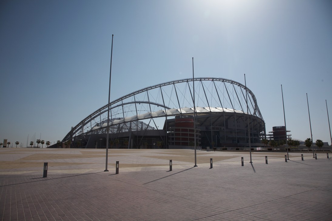 Khalifa International Stadium with distinctive curved white cable-stayed roof structure set against desert landscape.