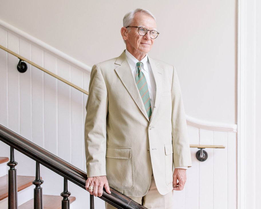 Charleston mayor Joseph Riley in a cream suit and striped tie standing on a staircase.