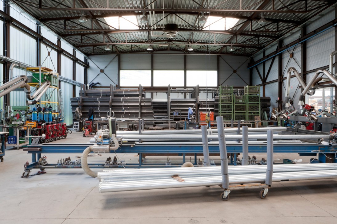 Industrial warehouse with steel lamp posts and manufacturing equipment on workbenches.