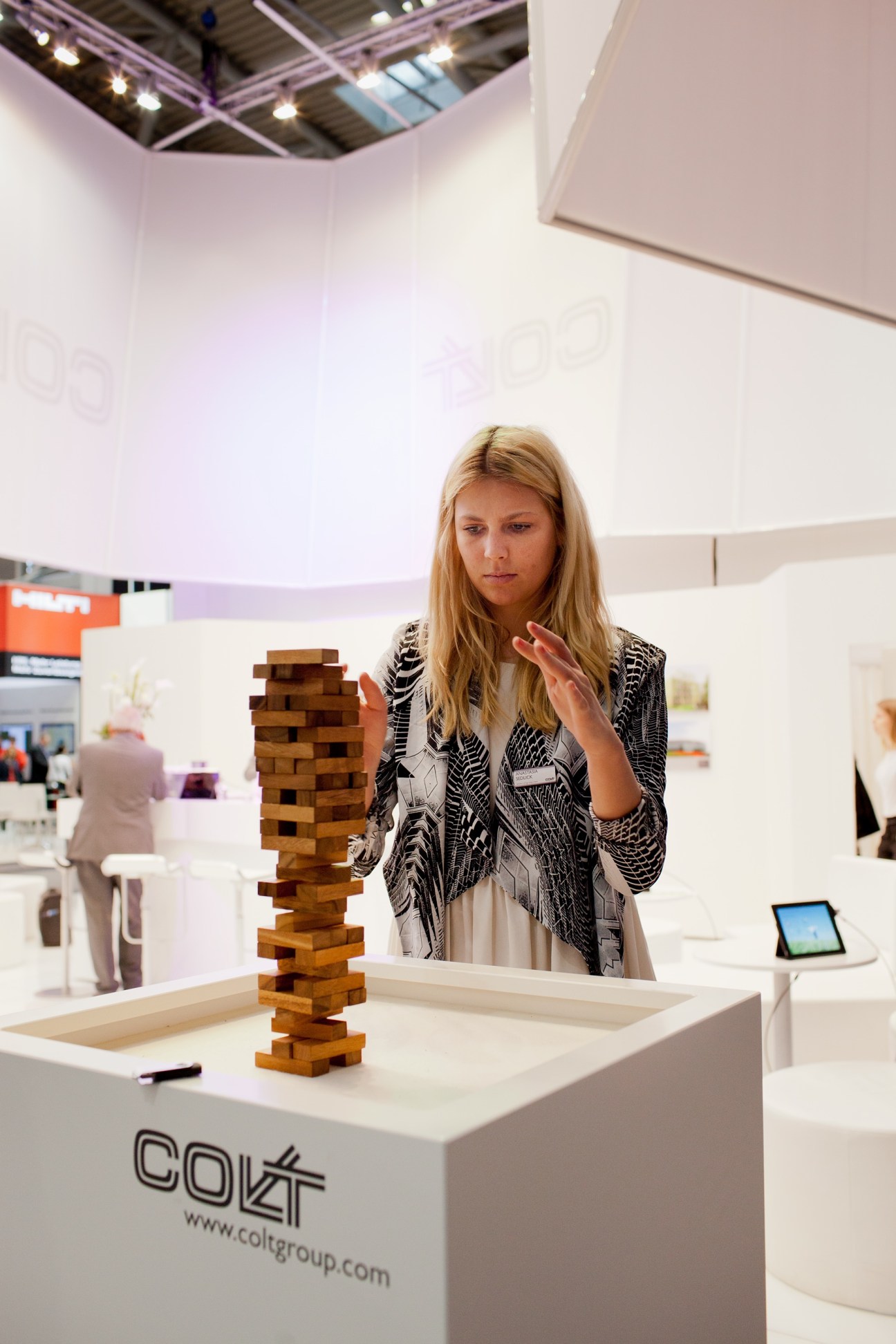 Woman playing with wooden building blocks at a COLT exhibitor booth at BAU trade fair.