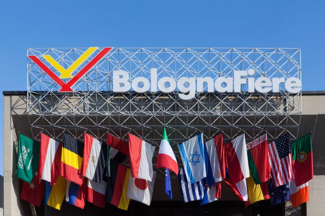 BolognaFiere entrance sign with colorful geometric logo above international flags from various countries
