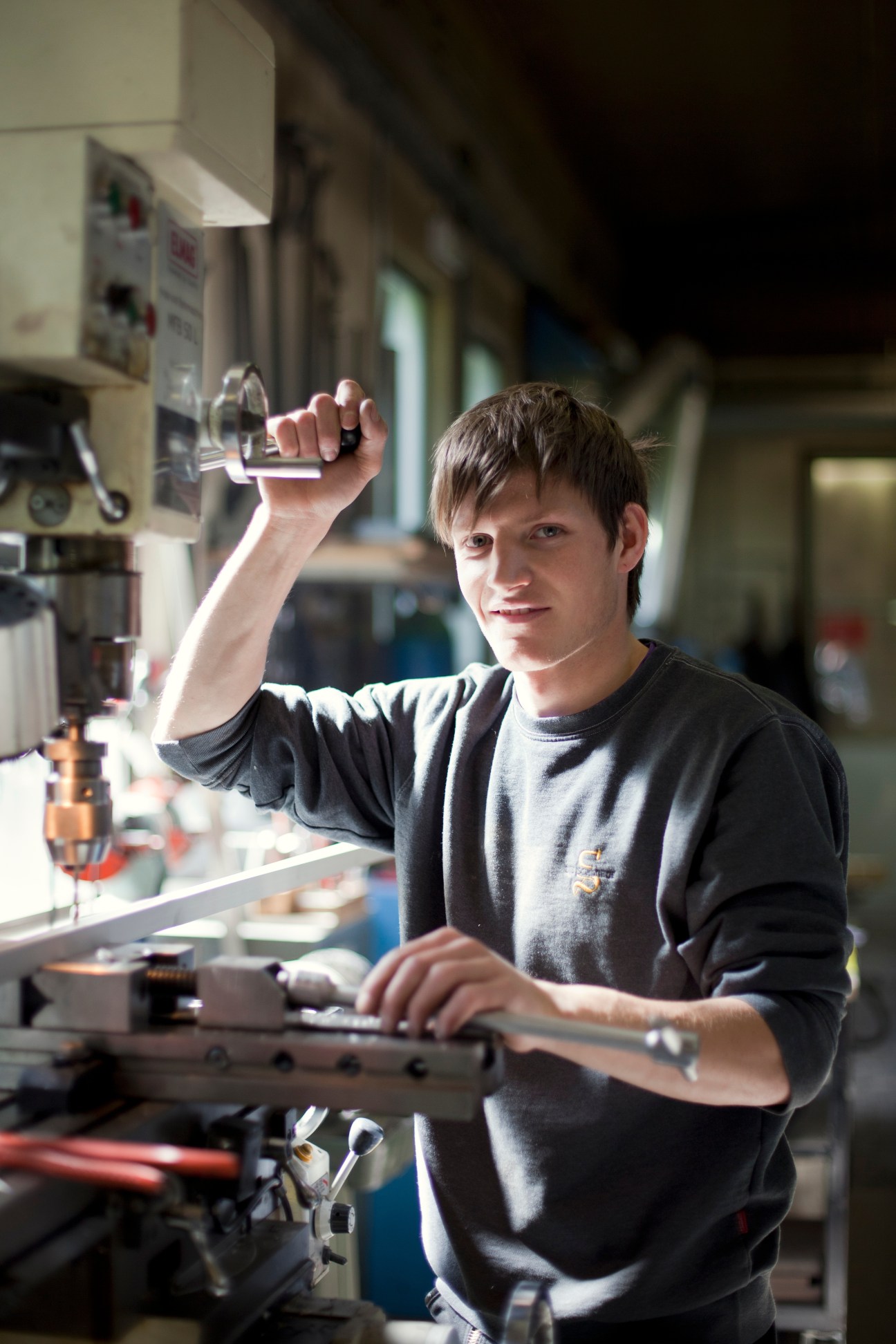 Factory worker drilling holes in a metal lamp component at Ewo's manufacturing facility.