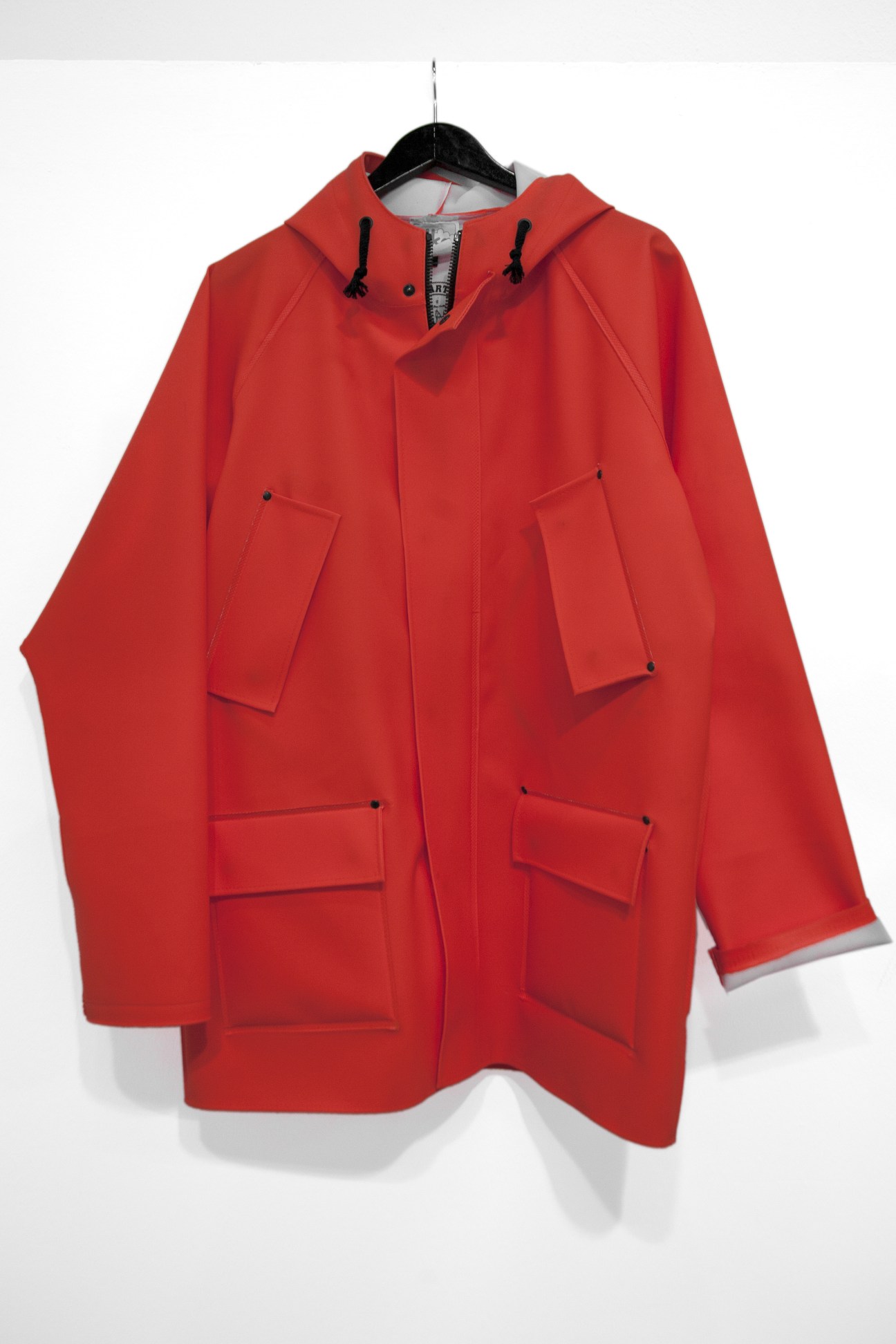Red hooded anorak jacket with patch pockets and black drawstring, displayed on a hanger.