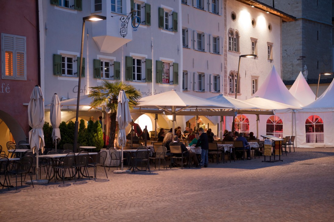Evening outdoor dining area in Caldaro lit by Ewo LED street lights mounted on poles