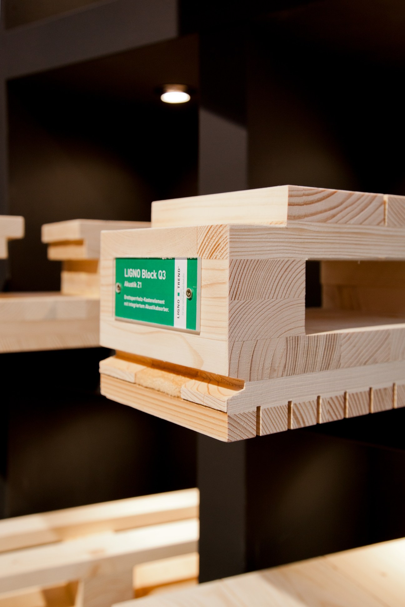 Stacked wooden building blocks labeled LIGNO Block 03 with visible wood grain patterns under spotlighting.
