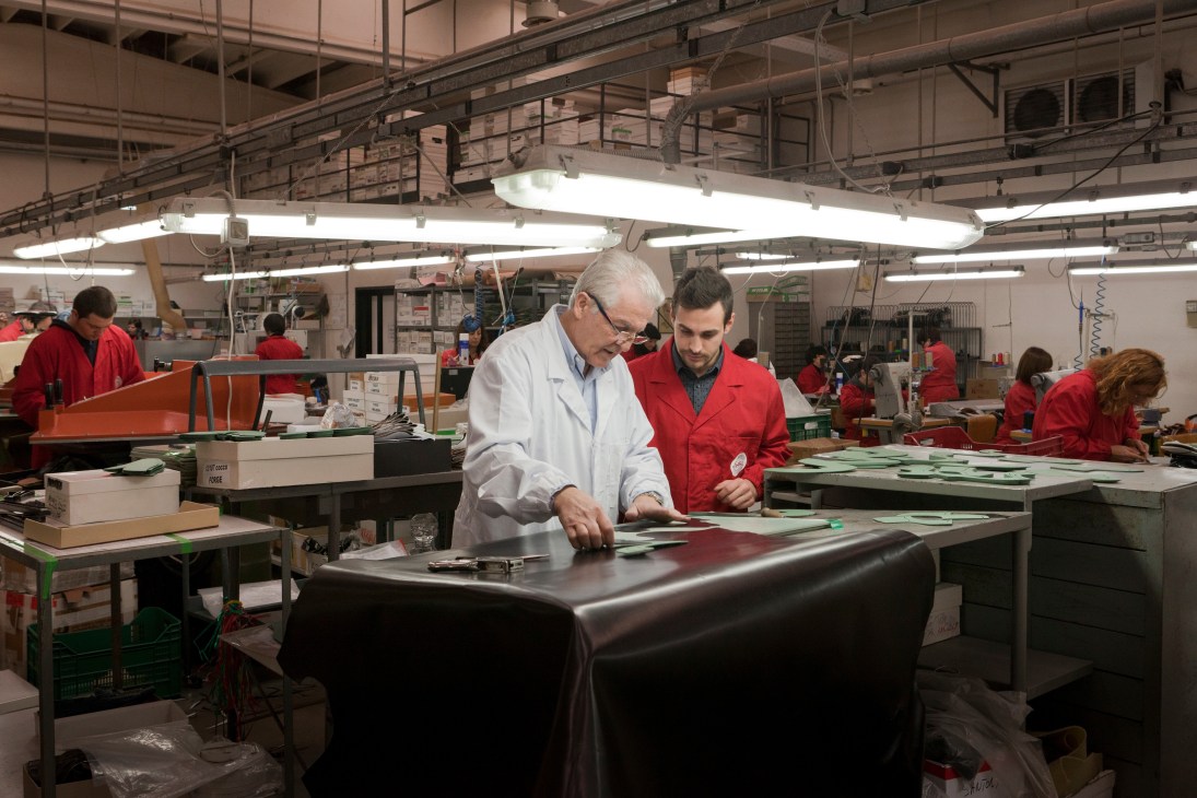 Master shoemaker Silvano Sollini instructs apprentice Matteo Valle at a workbench in the Santoni factory.